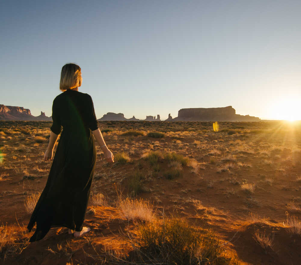 Femme marchant dans le désert de Monument Valley au coucher du soleil, paysage emblématique de l’Ouest américain