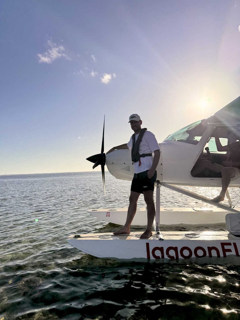Homme debout sur un hydravion au-dessus du lagon turquoise à l’île Maurice au coucher du soleil